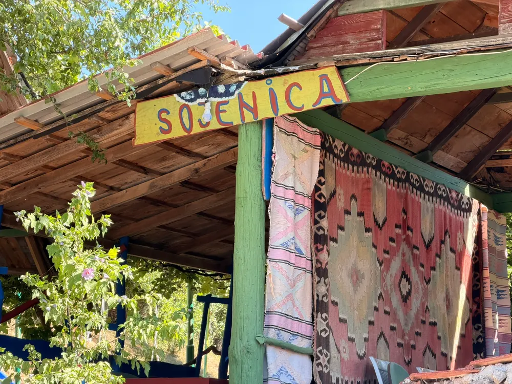 Natpis Sojenica i ćilimi na drvenom ulazu